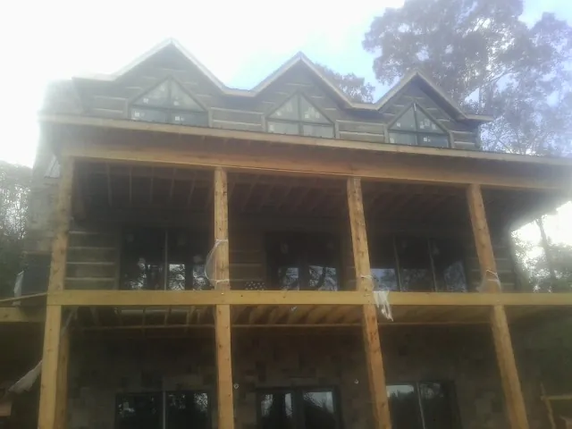 Dormers and porch framing on a large log home under construction — Roof Coating work by our crew in Cheney