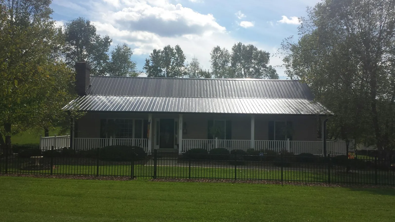 Gray metal roof on a brick ranch with a full width front porch — Gutter Guard Installation work by our crew in Cheney